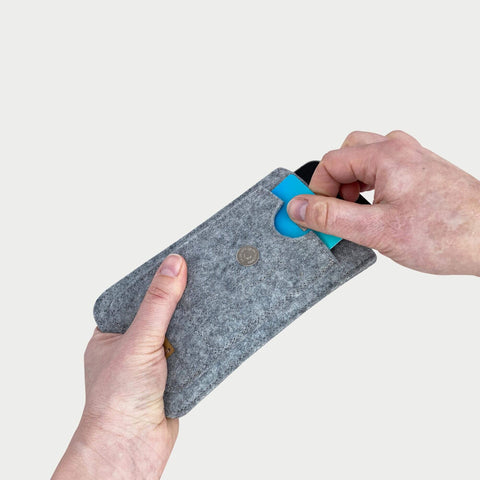 Hand, die eine hellgraue Handytasche für das Samsung Galaxy S25 FE hält, in die eine Karte eingelegt ist, wodurch das schlanke Design zur Geltung kommt.